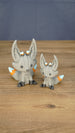 Two gray Palia Kitsuu Caldera plush figures in small and large sizes displayed together on a wooden tabletop.