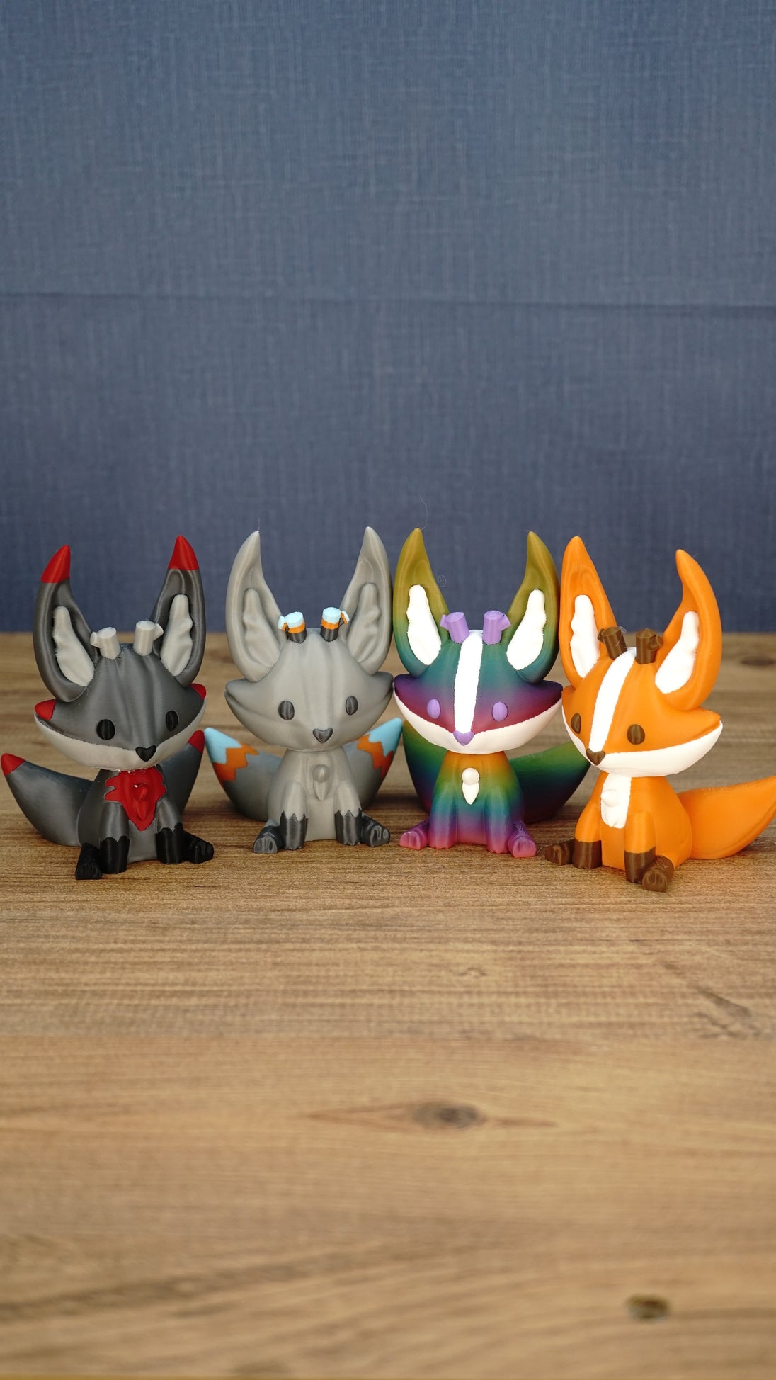 Lineup of Obsidian, Caldera, Rainbow, and Ancient Kitsuu figures displayed together on a wooden tabletop.