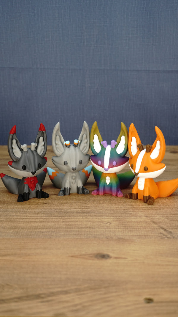Lineup of Obsidian, Caldera, Rainbow, and Ancient Kitsuu figures displayed together on a wooden tabletop.