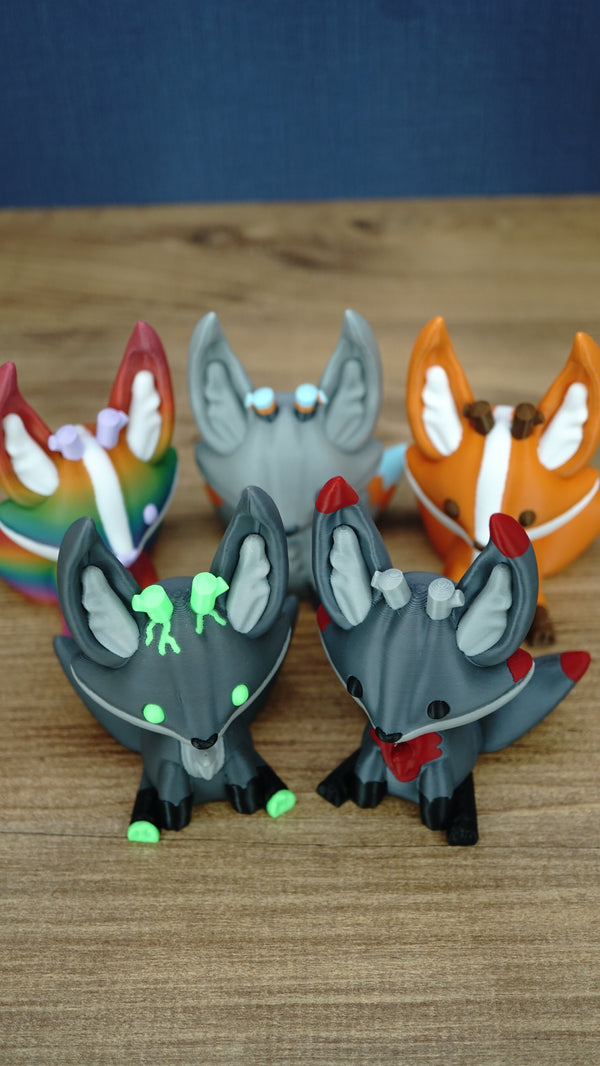 Close-up of five Palia Kitsuu figures, including Cave Kitsuu and other colourful variants, arranged on a wooden tabletop.