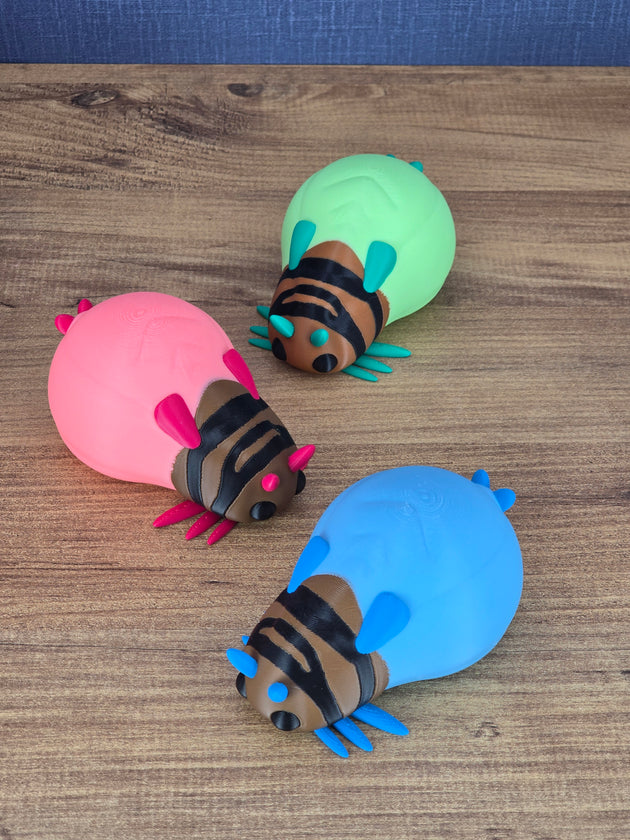 Three Palia-inspired glow lantern bug plush figures in pink, blue, and green displayed on a wooden tabletop.