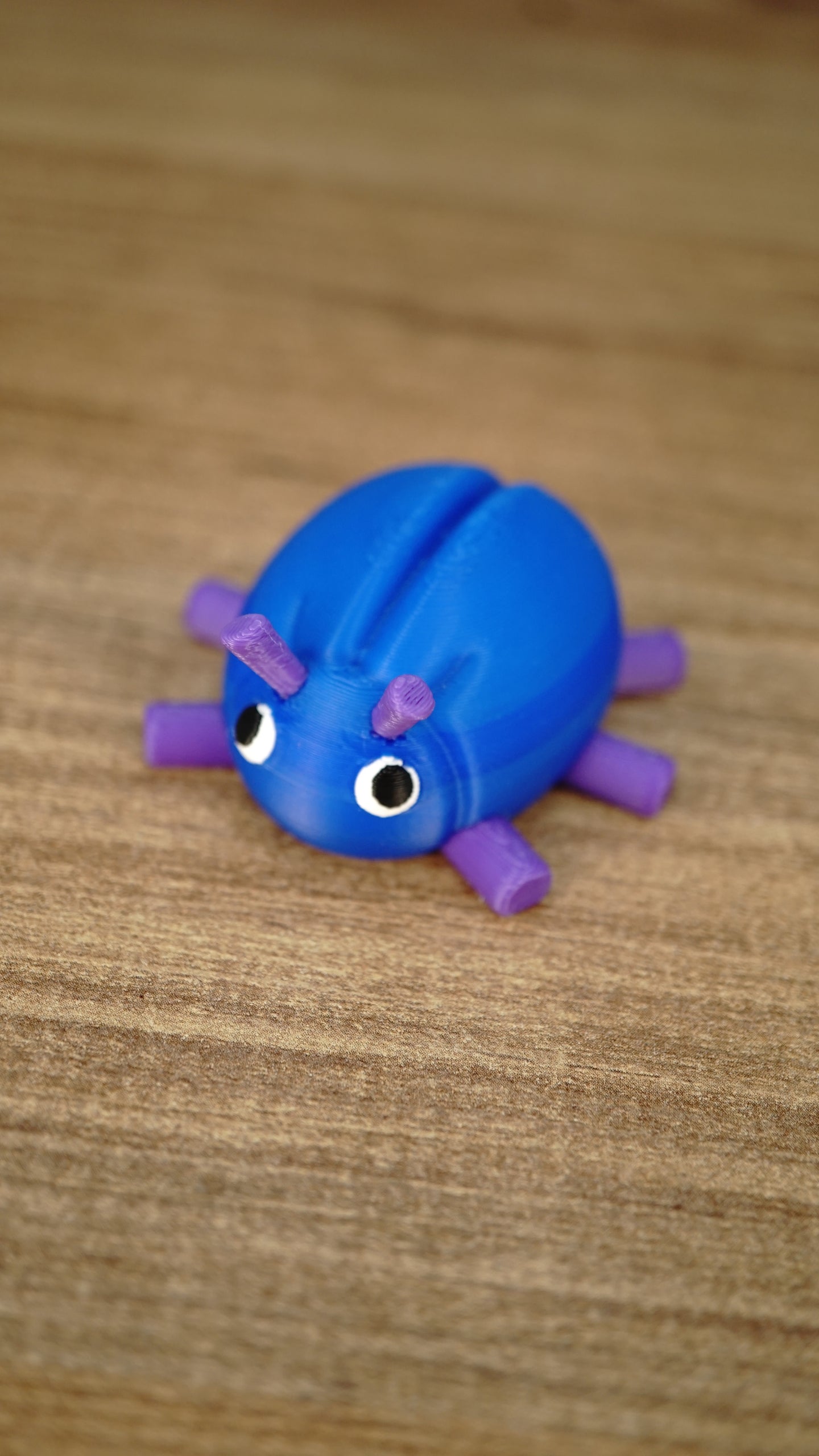 Close-up of the Li’l Beetle collectible miniature with a vivid blue shell, purple legs and antennae, and large expressive eyes.