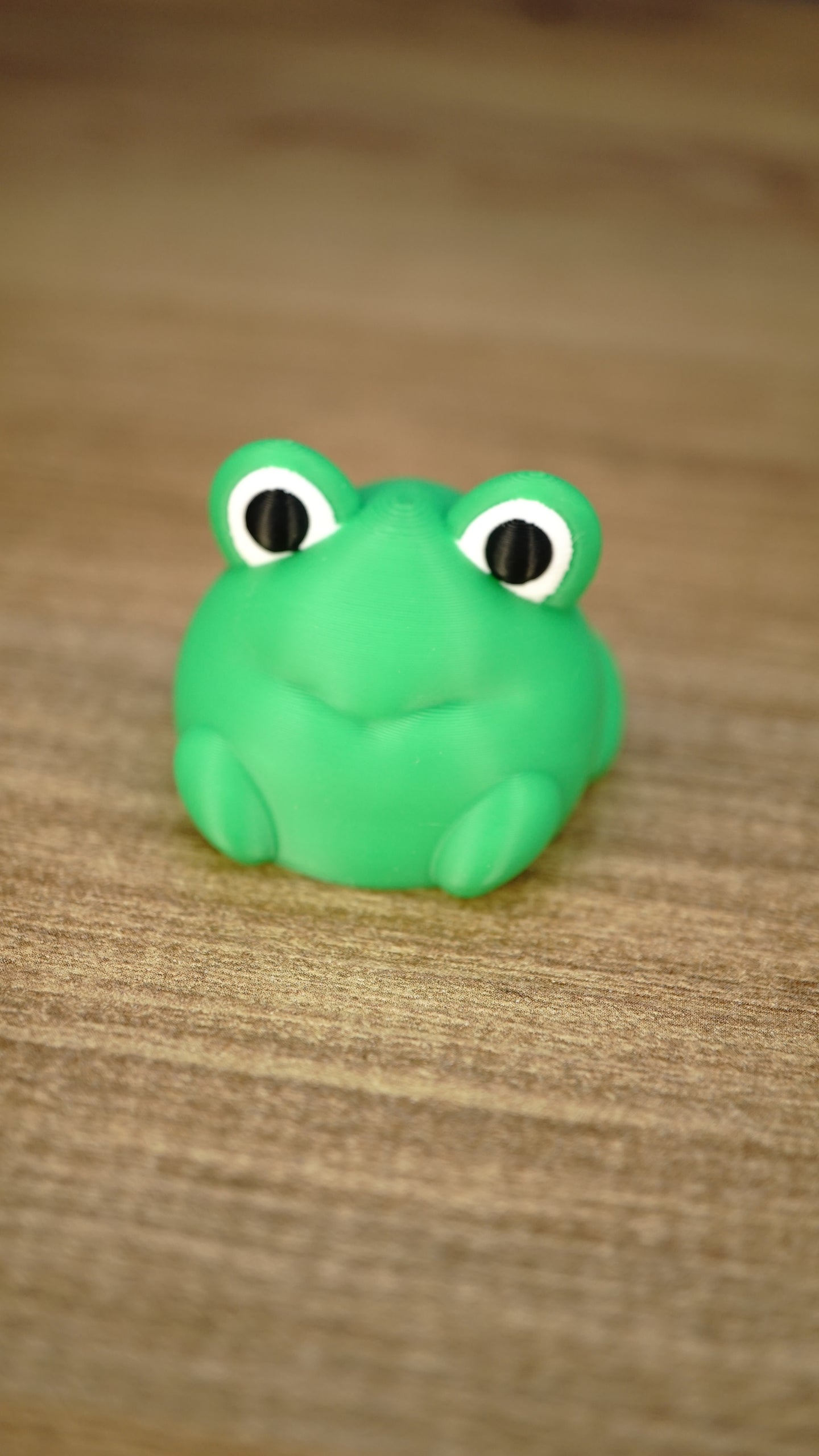 Close-up of the bright green Li’l Froggy collectible miniature with oversized black-and-white eyes, a subtle smile and tiny feet.