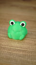 Close-up of the bright green Li’l Froggy collectible miniature with oversized black-and-white eyes, a subtle smile and tiny feet.