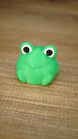 Close-up of the bright green Li’l Froggy collectible miniature with oversized black-and-white eyes, a subtle smile and tiny feet.