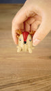 Hand holding the tan Li’l Sernuk miniature with brown antlers, red facial marking and small legs for an indication of its scale.