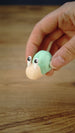 Hand holding the Li’l Snail miniature with a pale body, raised cartoon eyes and a rounded mint-green shell to demonstrate its size.