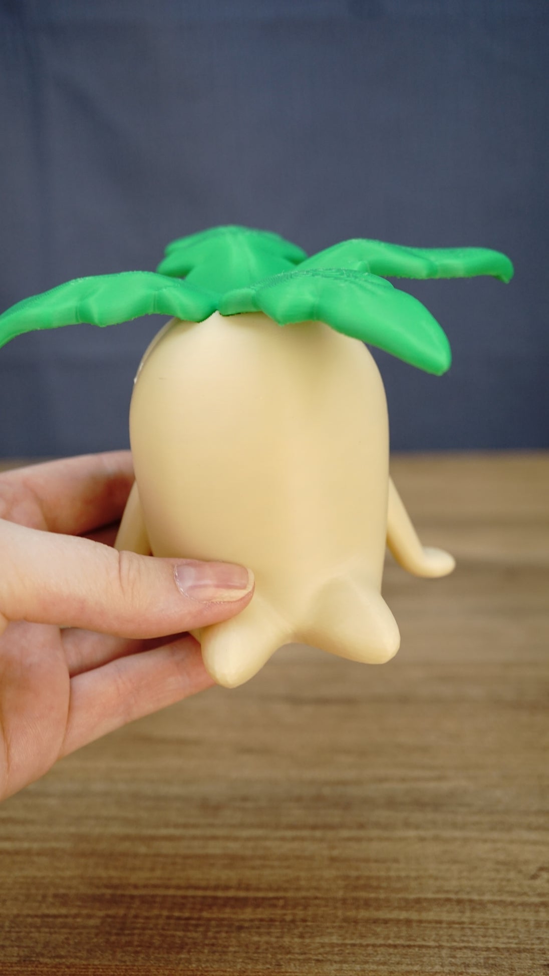 Large Palia Lil Sprout collectible held in one hand to demonstrate its scale, with a cream body and bright green leafy top clearly visible.