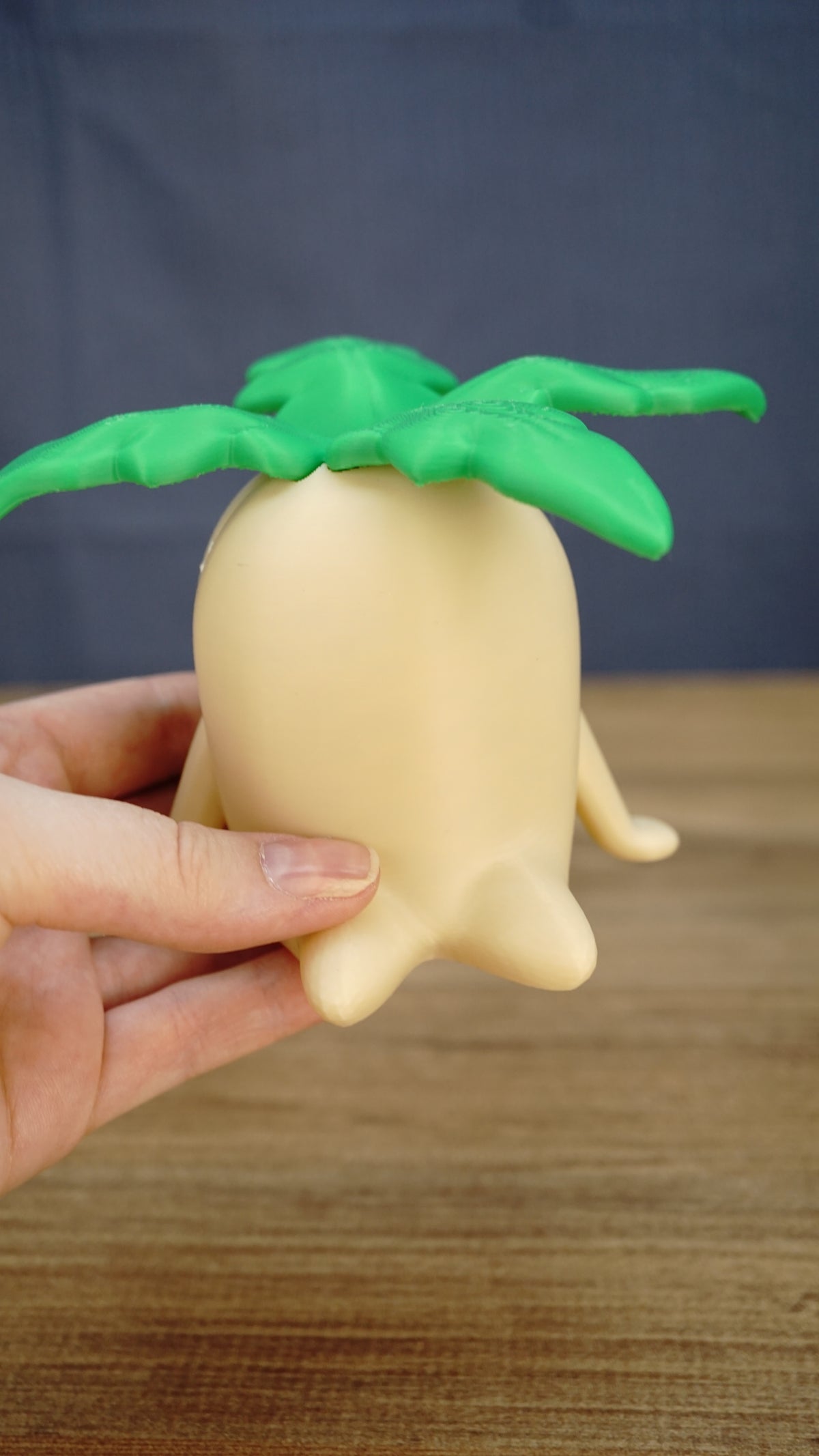 Large Palia Lil Sprout collectible held in one hand to demonstrate its scale, with a cream body and bright green leafy top clearly visible.