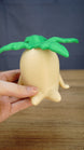 Large Palia Lil Sprout collectible held in one hand to demonstrate its scale, with a cream body and bright green leafy top clearly visible.
