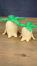 Palia Lil Sprout collectible figures in two sizes displayed side by side, featuring cream vegetable-shaped bodies and oversized green leaves