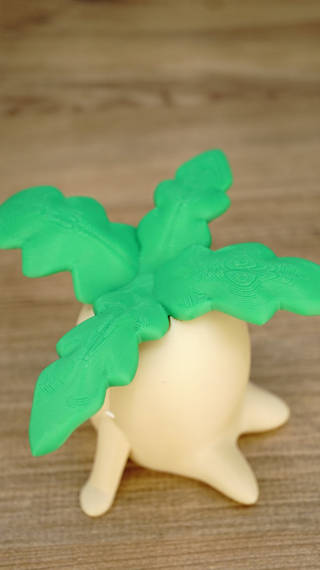 Close-up top view of the Palia Lil Sprout collectible showing the detailed bright green layered leaves above its cream-coloured body.