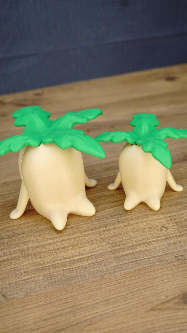 Angled view of small and large Palia Lil Sprout fan-made figures showing their green leafy tops, cream bodies and cute sprout-shaped feet.