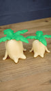 Angled view of small and large Palia Lil Sprout fan-made figures showing their green leafy tops, cream bodies and cute sprout-shaped feet.