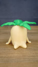 Front view of the large Palia Lil Sprout collectible figure with a rounded cream body, small side legs and wide bright green leafy sprout top.