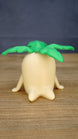 Front view of the large Palia Lil Sprout collectible figure with a rounded cream body, small side legs and wide bright green leafy sprout top.
