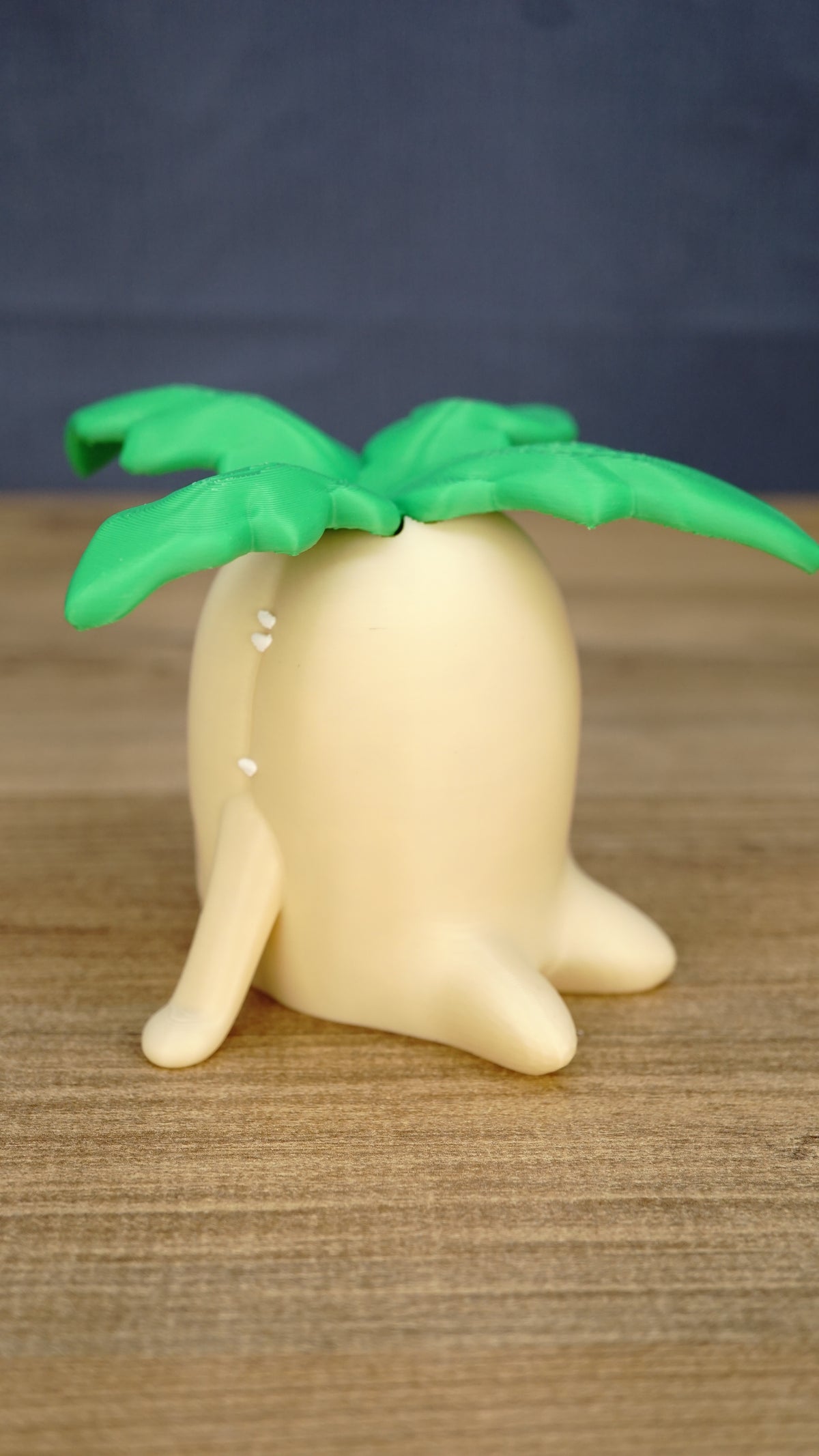 Side view of the large Palia Lil Sprout fan-made collectible showing the rounded cream body, little feet and layered green leaves on top.