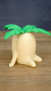 Side view of the large Palia Lil Sprout fan-made collectible showing the rounded cream body, little feet and layered green leaves on top.