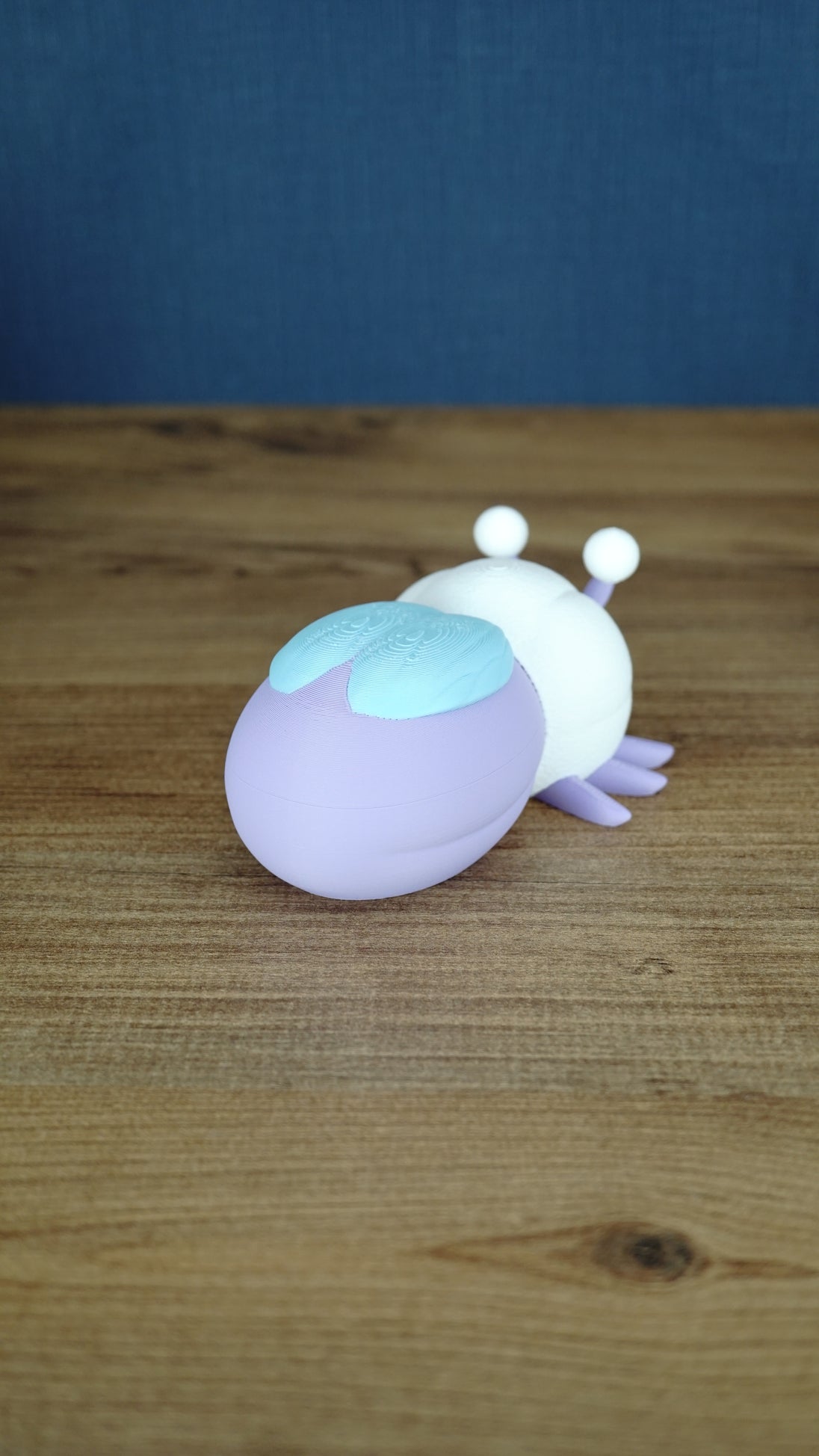 Back view of a 3D printed Palia Luna Moth plush showing its rounded lavender body, light blue wings, and white head.