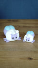 Large and small 3D printed Palia Luna Moth plush figures in pastel purple, white, and light blue on a wooden tabletop.
