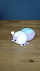 Side view of a pastel purple and white 3D printed Palia Luna Moth plush showing its light blue wing detail and lavender legs.