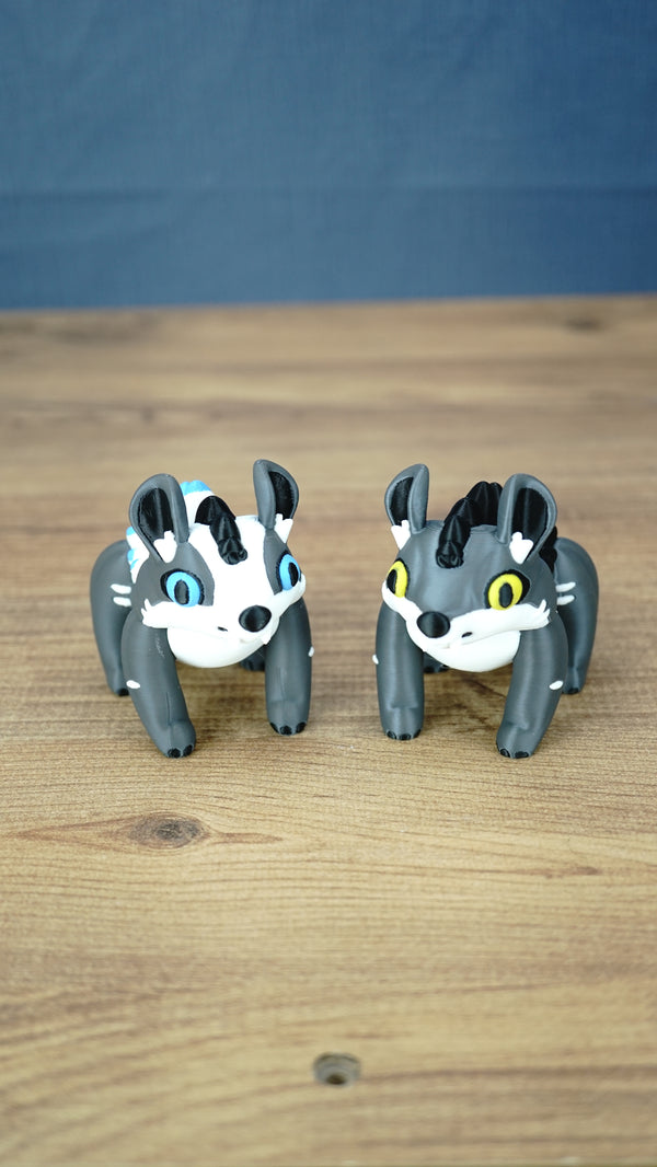 Palia Muujin and Bluebristle Muujin plush-inspired collectible figures displayed together, showing yellow and blue eyes with detailed grey bodies and contrasting manes.

