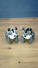 Palia Muujin and Bluebristle Muujin plush-inspired collectible figures displayed together, showing yellow and blue eyes with detailed grey bodies and contrasting manes.
