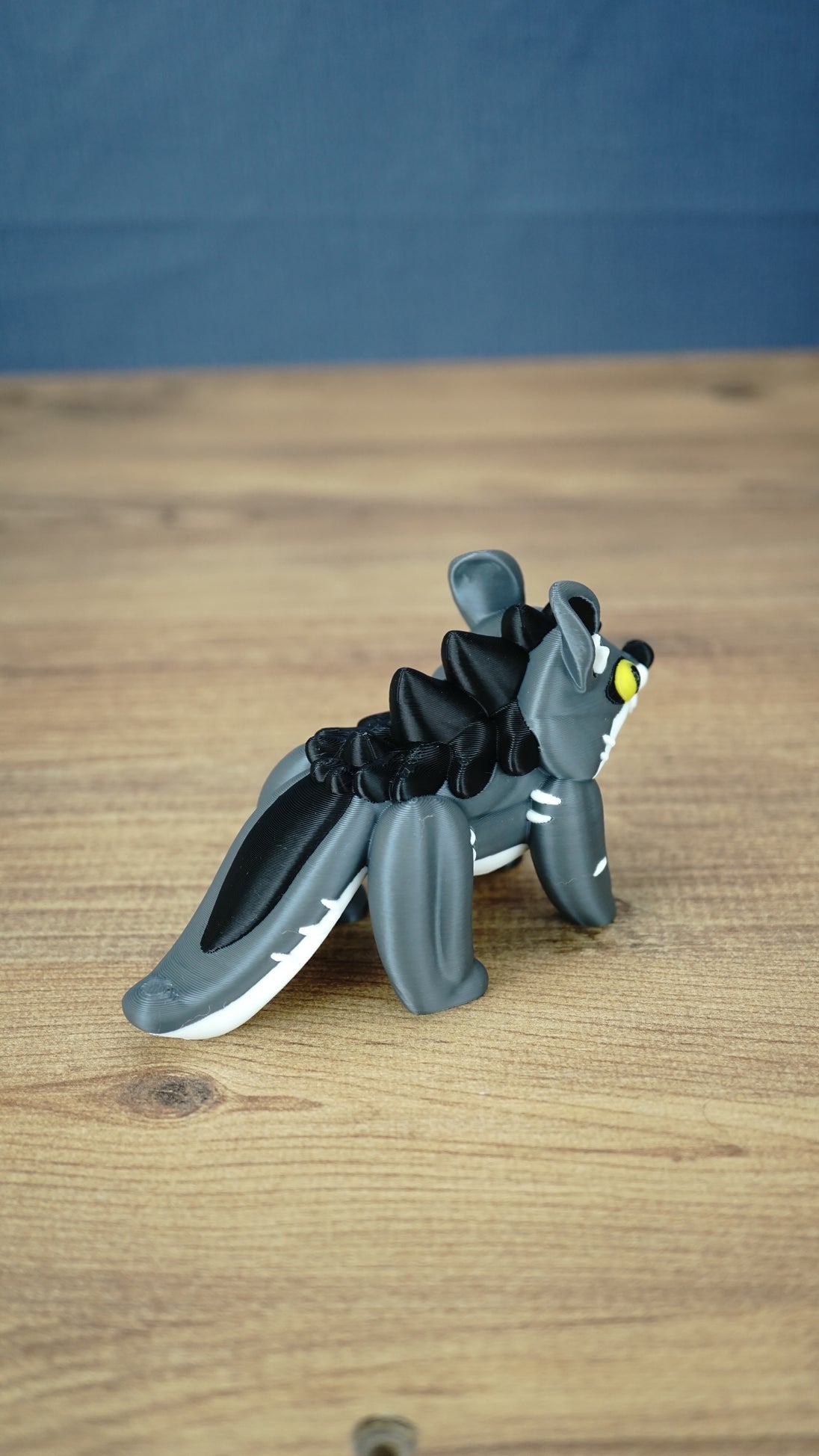 Rear three-quarter view of the Palia Muujin collectible figure highlighting its long grey and white tail, dark spiky mane and sculpted fantasy creature details