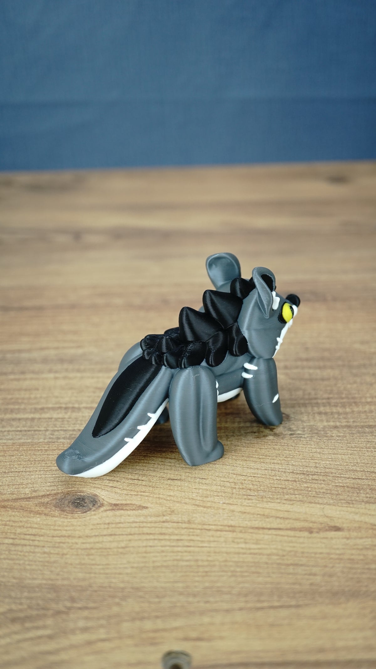Rear three-quarter view of the Palia Muujin collectible figure highlighting its long grey and white tail, dark spiky mane and sculpted fantasy creature details