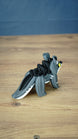 Rear three-quarter view of the Palia Muujin collectible figure highlighting its long grey and white tail, dark spiky mane and sculpted fantasy creature details