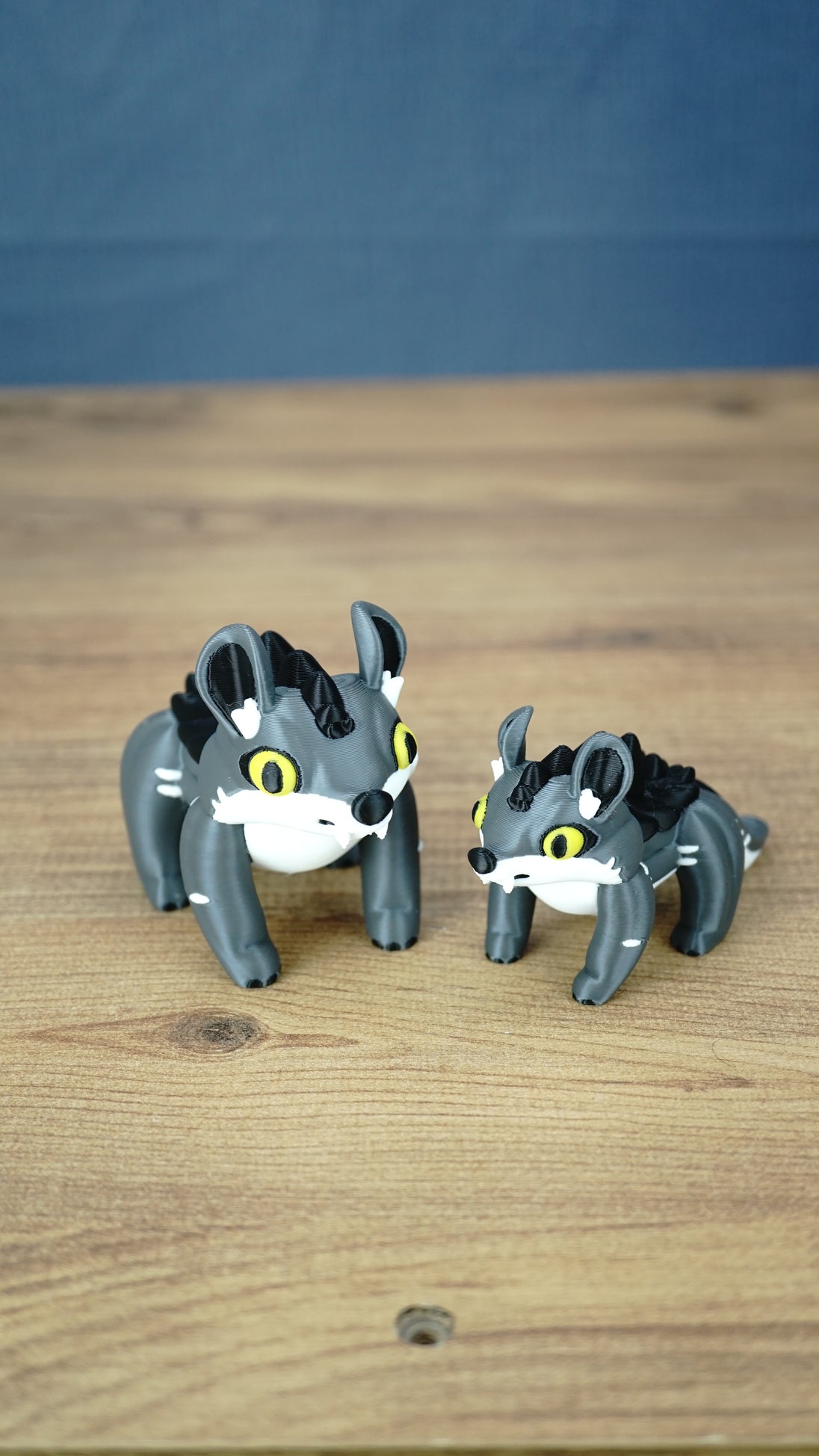 Large and small Palia Muujin collectible figurines with yellow eyes, grey bodies and black spiky manes, showing the 12 cm and 9 cm size options.