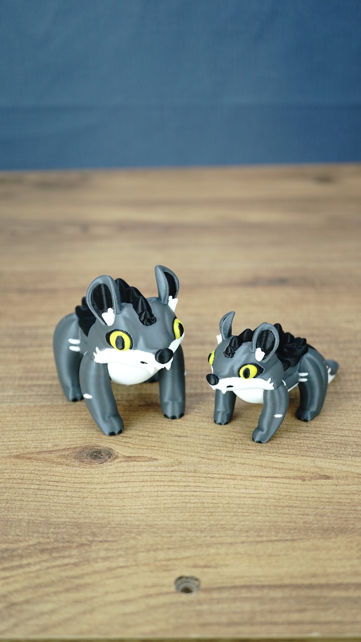 Large and small Palia Muujin collectible figurines with yellow eyes, grey bodies and black spiky manes, showing the 12 cm and 9 cm size options.