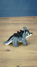 Full side profile of the yellow-eyed Palia Muujin figurine showing its grey body, black back spikes, pointed ears, white facial markings and long tail.