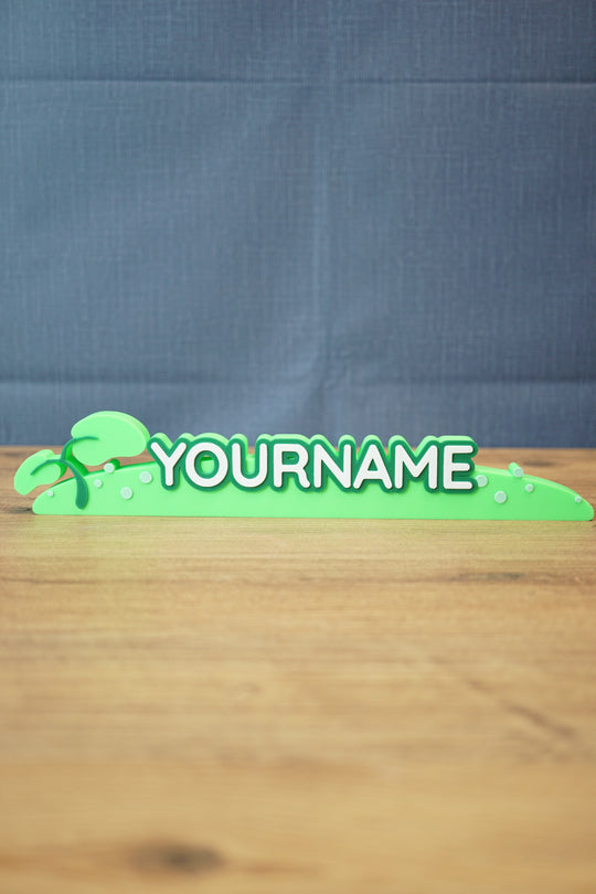 Palia New in Town nameplate sign shown from the front with green leafy details, raised white lettering, and a slim 25cm display shape.