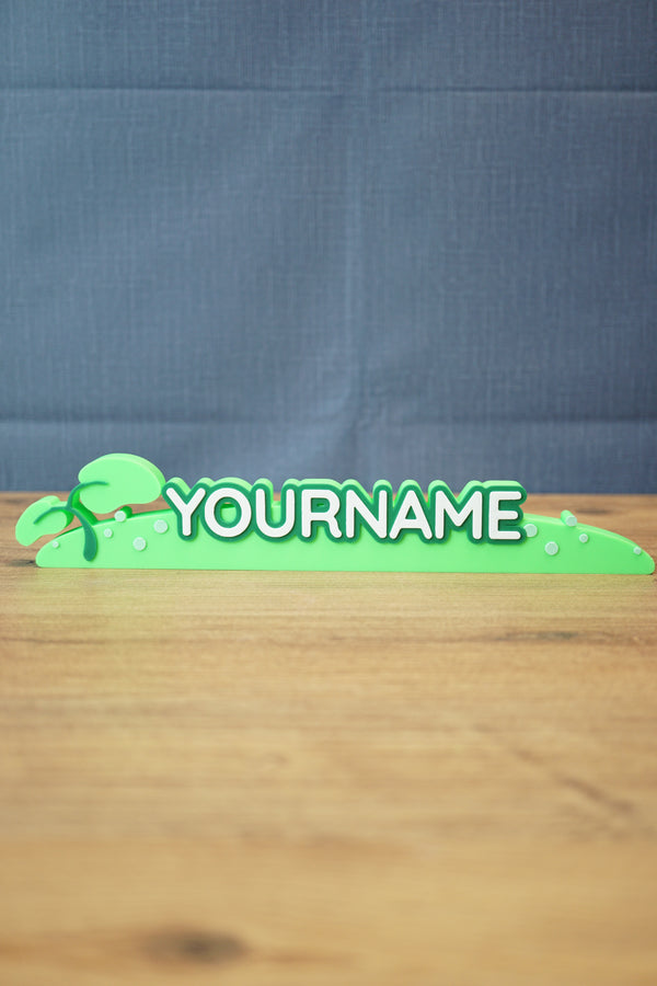 Palia New in Town nameplate sign shown from the front with green leafy details, raised white lettering, and a slim 25cm display shape.