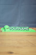 Palia New in Town nameplate sign shown from the front with green leafy details, raised white lettering, and a slim 25cm display shape.