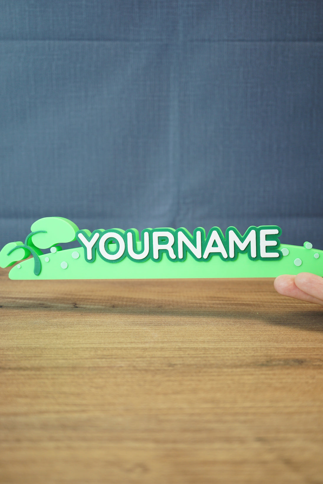 Front view of the Palia New in Town nameplate sign being held to show scale, with bold raised letters and bright green decorative base.