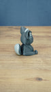 Back side view of a 3D printed Nox the Palcat plush figure showing the curled grey tail with pale tip, seated pose, and large pointed ears.