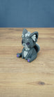 Side view of a 3D printed Nox the Palcat plush figure showing its curled tail, large ears, pale grey head details, and purple paw pads.