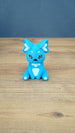 Front view of a bright blue 3D printed One-in-Ten-Million Palcat plush figure with white chest, ear details, paw pads, black eyes, and tiny white fangs.