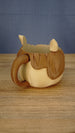 Rear side view of the Palia-inspired Ormuu ice cream holder displaying the curved carrying handle, character ear and textured brown hair details.