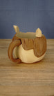 Rear side view of the Palia-inspired Ormuu ice cream holder displaying the curved carrying handle, character ear and textured brown hair details.
