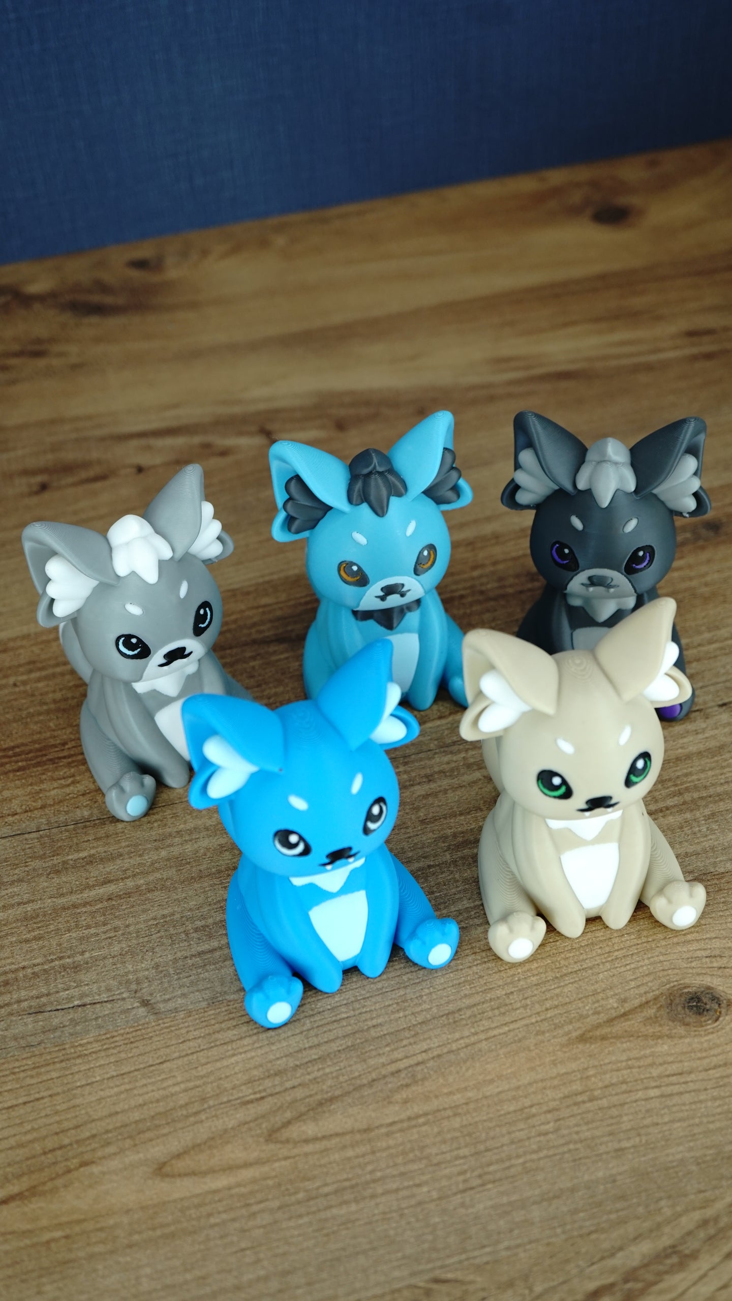 Angled view of five 3D printed Palcat plush figures from Palia arranged together on a wooden tabletop.