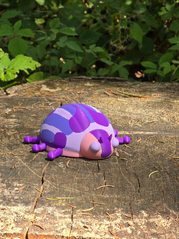 Palia Princess Ladybug collectible displayed outdoors on a woodland tree stump, showing its purple, pink, blue and white design in natural surroundings