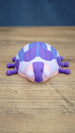 Front view of the Palia Princess Ladybug collectible with large white eyes, pink face, purple markings and a rounded blue and white patterned shell