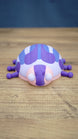 Front view of the Palia Princess Ladybug collectible with large white eyes, pink face, purple markings and a rounded blue and white patterned shell