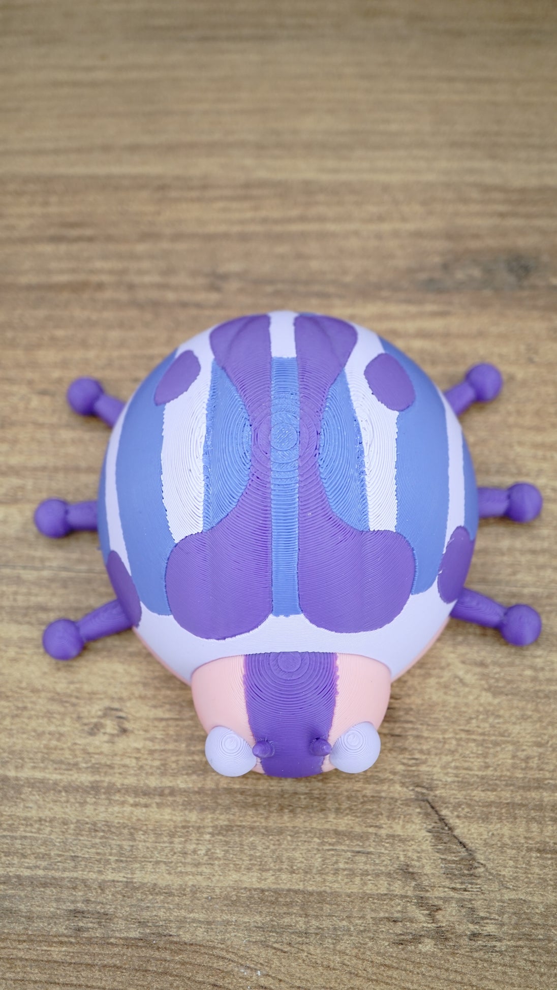 Top view of the Palia Princess Ladybug collectible showing symmetrical purple and blue shell markings, pink body and six purple ladybug legs