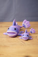 Two purple Palia Prismfish 3D printed figures displayed on a wooden tabletop with a blue fabric background.