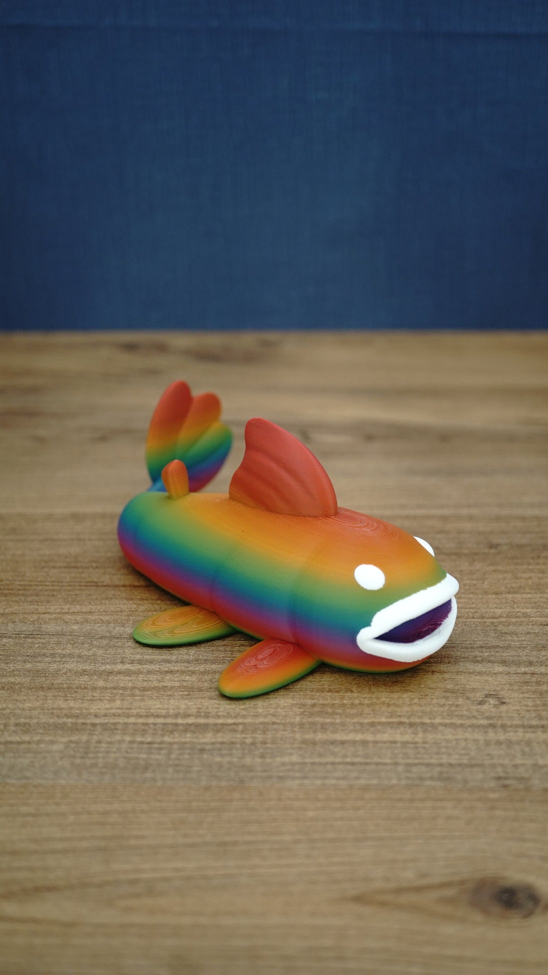 Large rainbow Palia Prismfish 3D printed figure shown from the side, with orange, green, blue, and purple colouring.