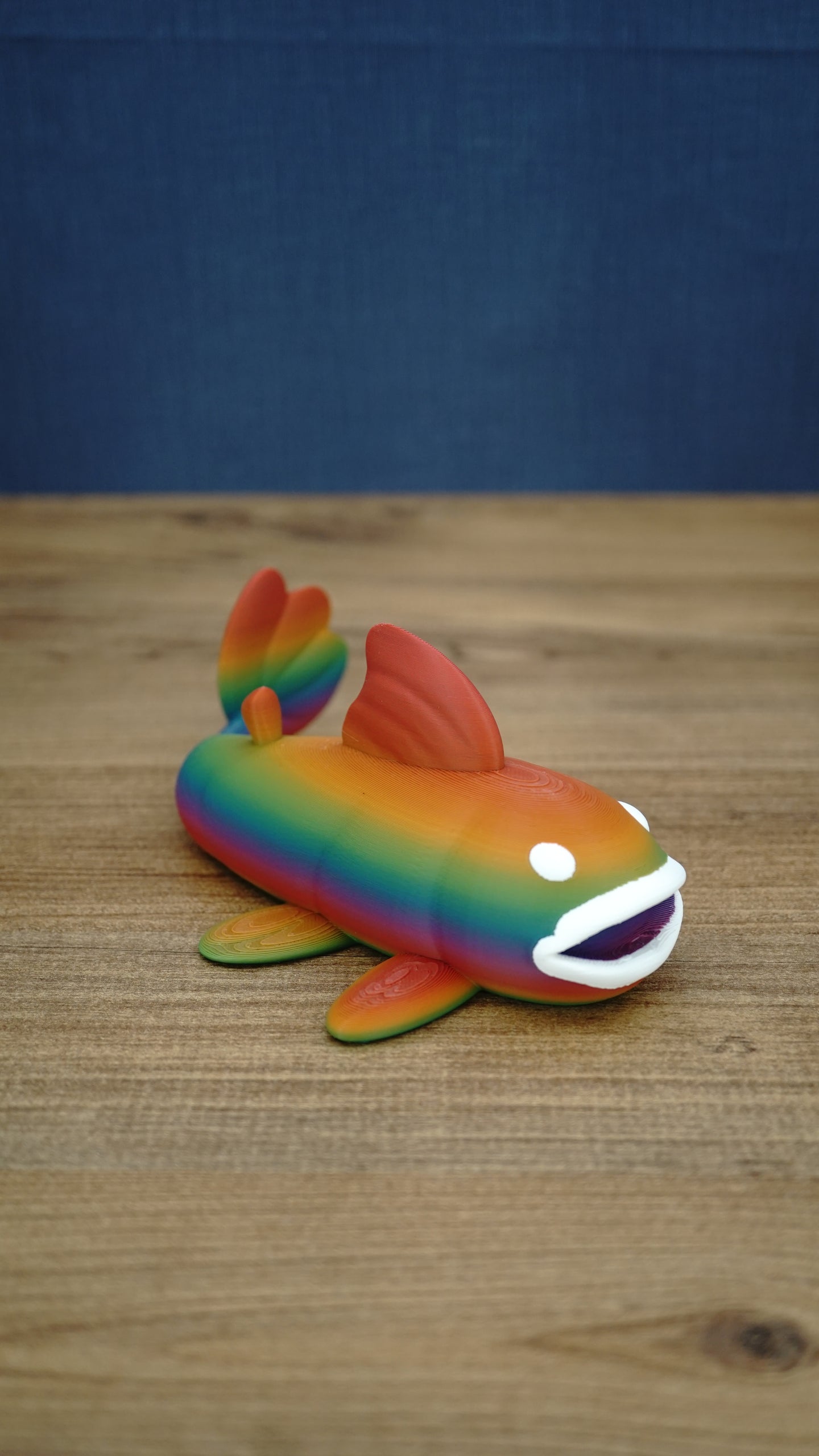 Large rainbow Palia Prismfish 3D printed figure shown from the side, with orange, green, blue, and purple colouring.